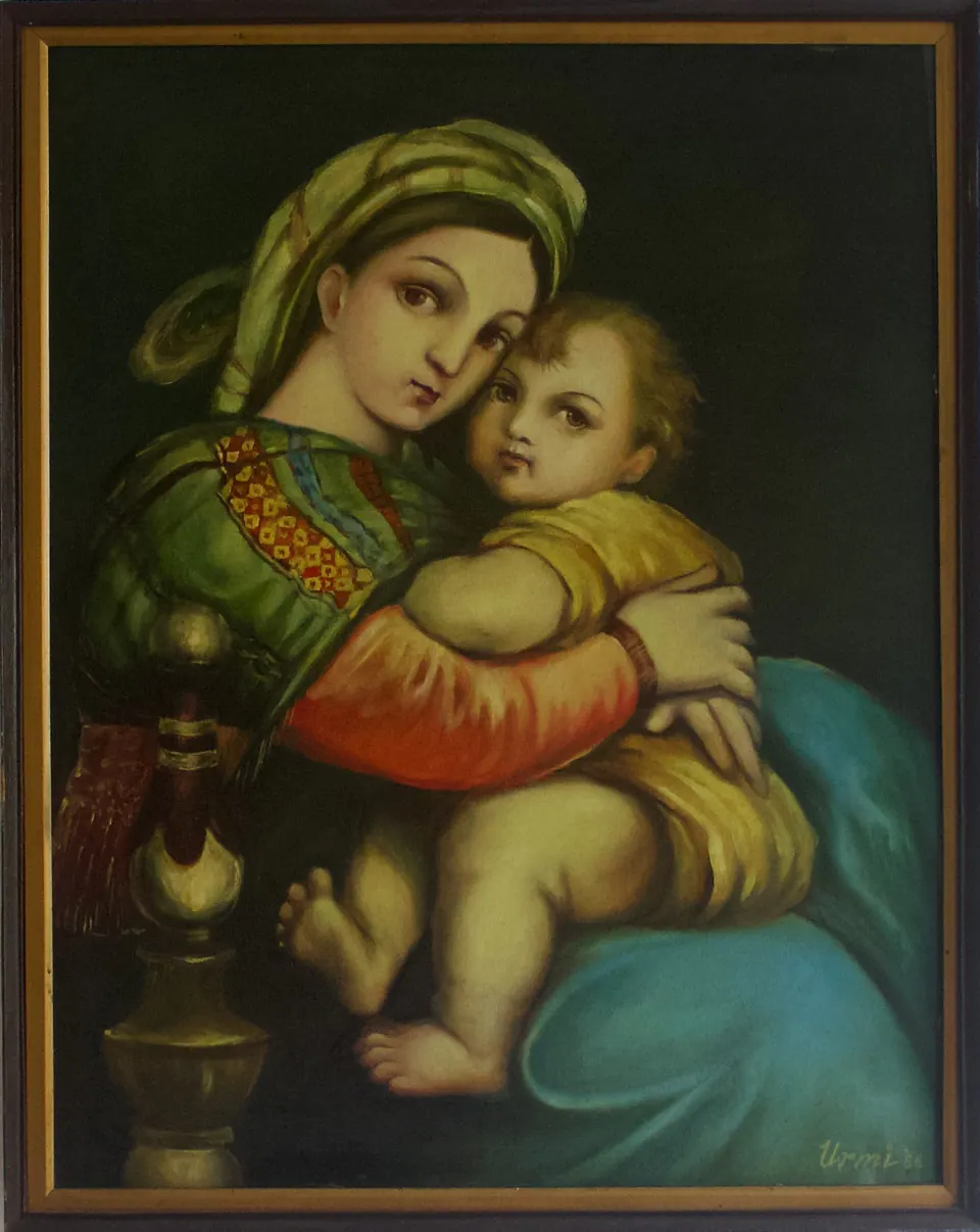 Mother in green and red clothing holding a child against a dark background with bright blue drapery.